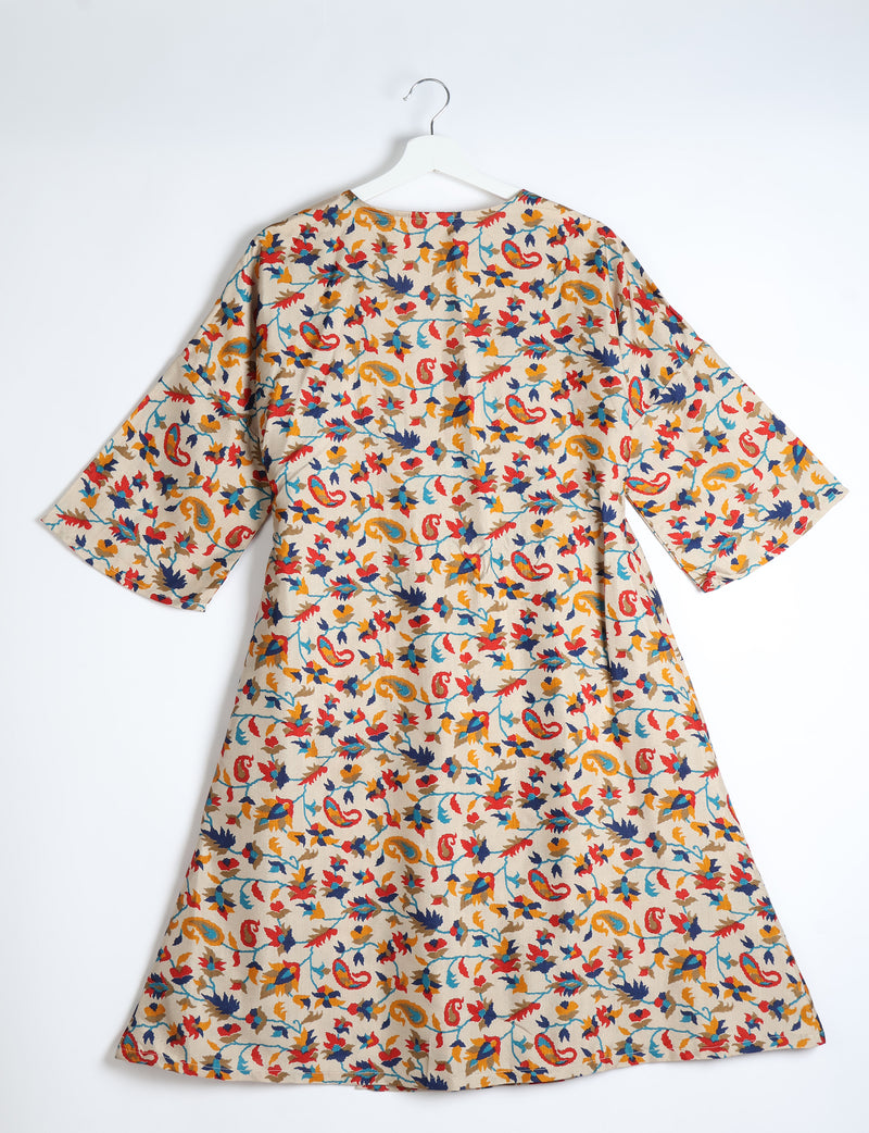 Beige coat with multicolor paisley and floral print, wide sleeves, shown from back on white hanger against white background