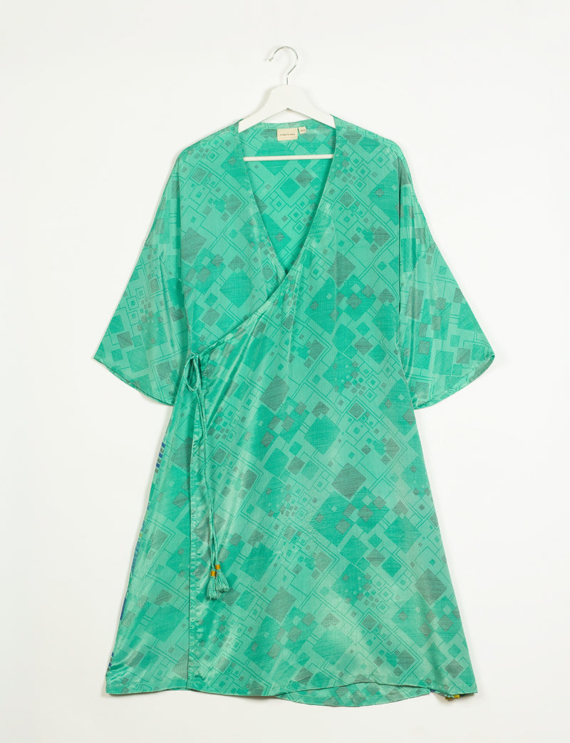 Green geometric patterned wrap coat with wide sleeves and side tie, hanging on white hanger against white background