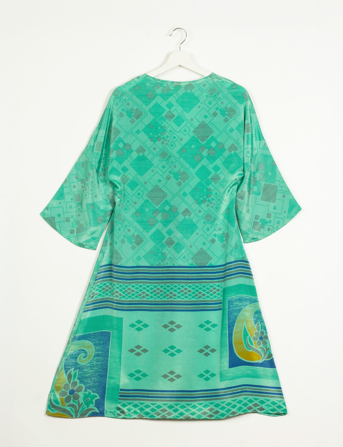 Green geometric patterned coat with wide sleeves hanging on white hanger, back view, featuring blue and yellow border designs