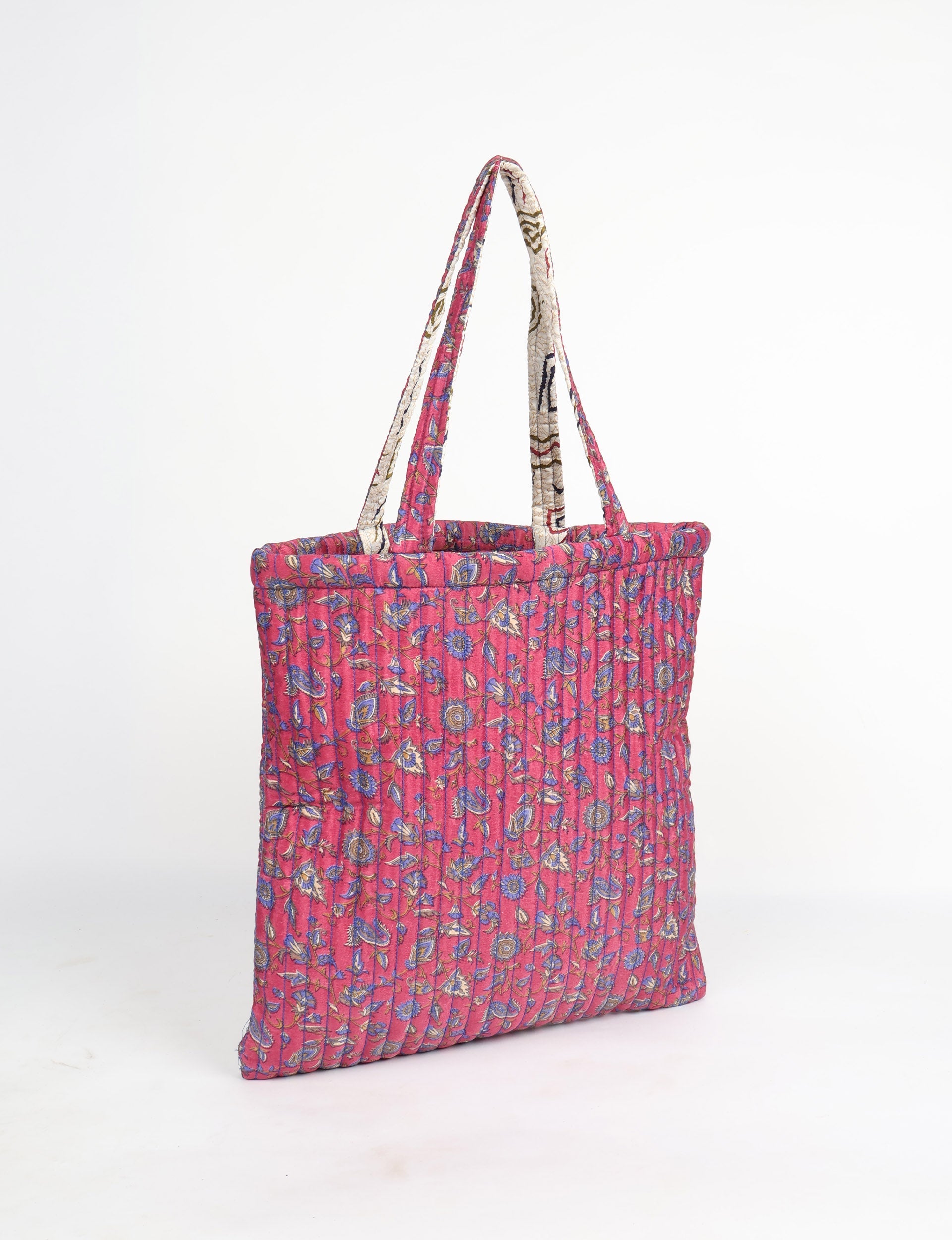 Quilted pink tropical floral shopper bag with vertical stitching and dual fabric handles, shown in side view on white background