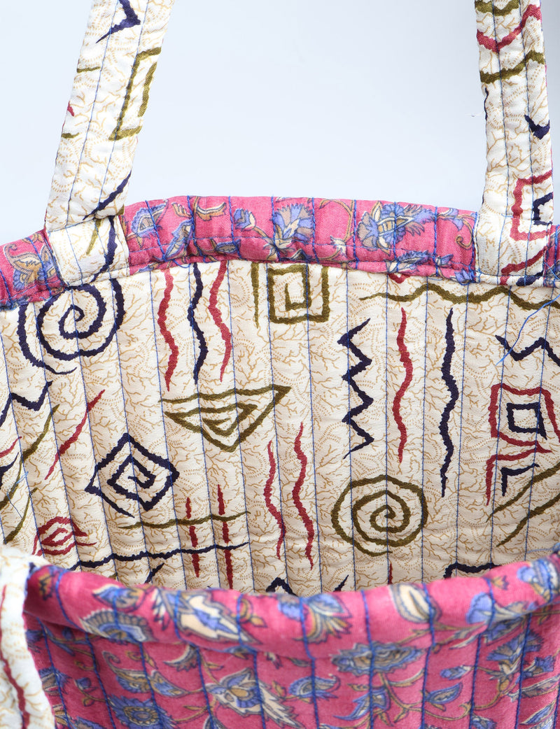 Quilted shopper bag with pink floral trim and cream base featuring multicolor abstract and spiral patterns, shown close-up
