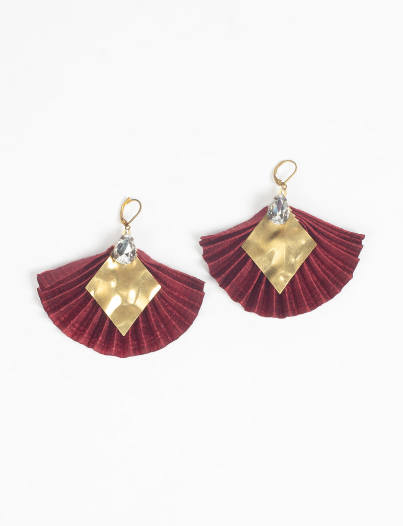 Red pleated fabric earrings with hammered gold diamond-shaped metal and clear teardrop crystals, shown flat on white background