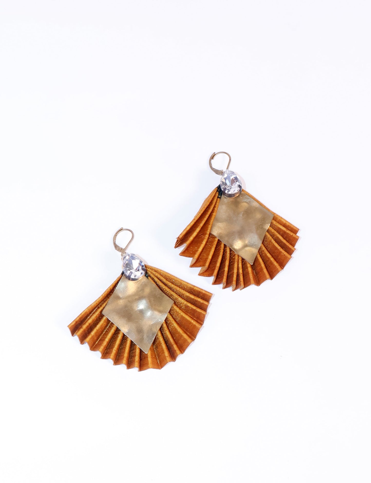 Elevate your style sustainably with our PLEATED EARRINGS – a fusion of ethical fashion and eco-conscious design. Created from pre-loved saris using heat set pleats, these earrings embody zero waste clothing and upcycled fashion. Fastened with hooks, adorned with a diamond-shaped metallic plate and a special drop-shaped jewel. Hypoallergy tested metal hooks, nickel, and lead-free, making them a conscious and skin-friendly accessory.