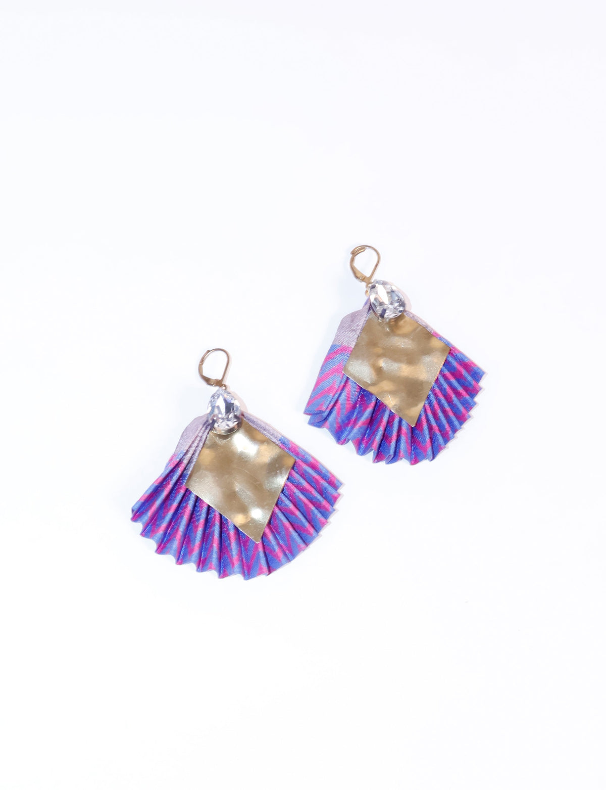 Pair of pleated earrings with blue and pink abstract pattern, gold-tone hammered metal, and clear teardrop crystals, flat lay view