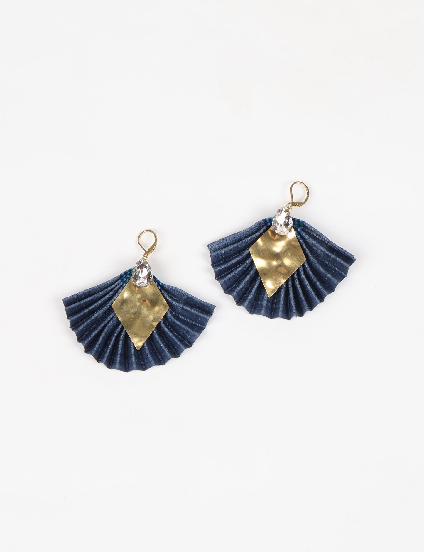 Elevate your style sustainably with our PLEATED EARRINGS – a fusion of ethical fashion and eco-conscious design. Created from pre-loved saris using heat set pleats, these earrings embody zero waste clothing and upcycled fashion. Fastened with hooks, adorned with a diamond-shaped metallic plate and a special drop-shaped jewel. Hypoallergy tested metal hooks, nickel, and lead-free, making them a conscious and skin-friendly accessory.