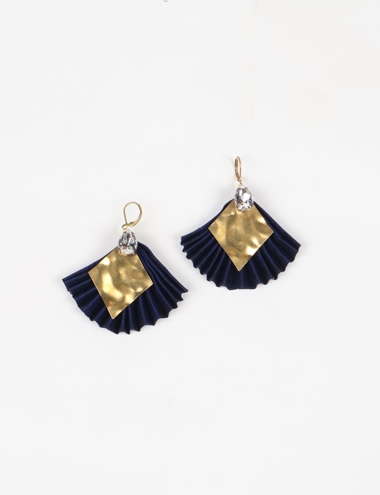 Elevate your style sustainably with our PLEATED EARRINGS – a fusion of ethical fashion and eco-conscious design. Created from pre-loved saris using heat set pleats, these earrings embody zero waste clothing and upcycled fashion. Fastened with hooks, adorned with a diamond-shaped metallic plate and a special drop-shaped jewel. Hypoallergy tested metal hooks, nickel, and lead-free, making them a conscious and skin-friendly accessory.