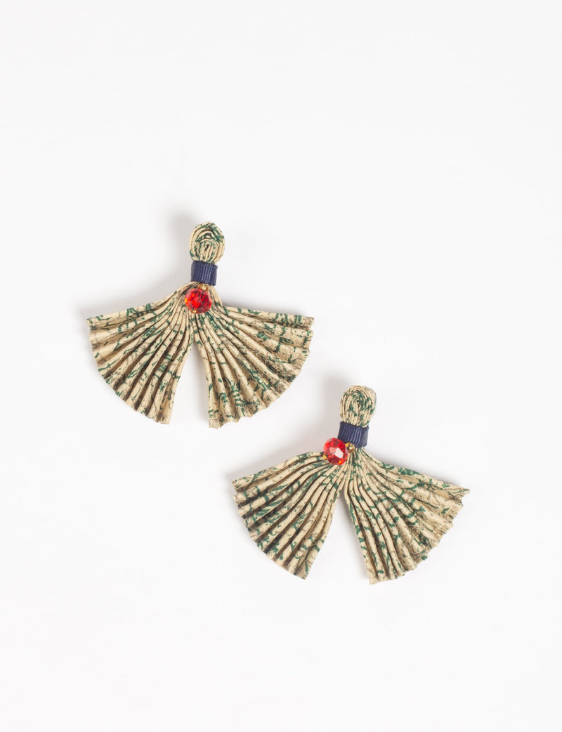 Beige pleated fabric earrings with green abstract print, navy blue band, and red faceted bead detail, flat lay view