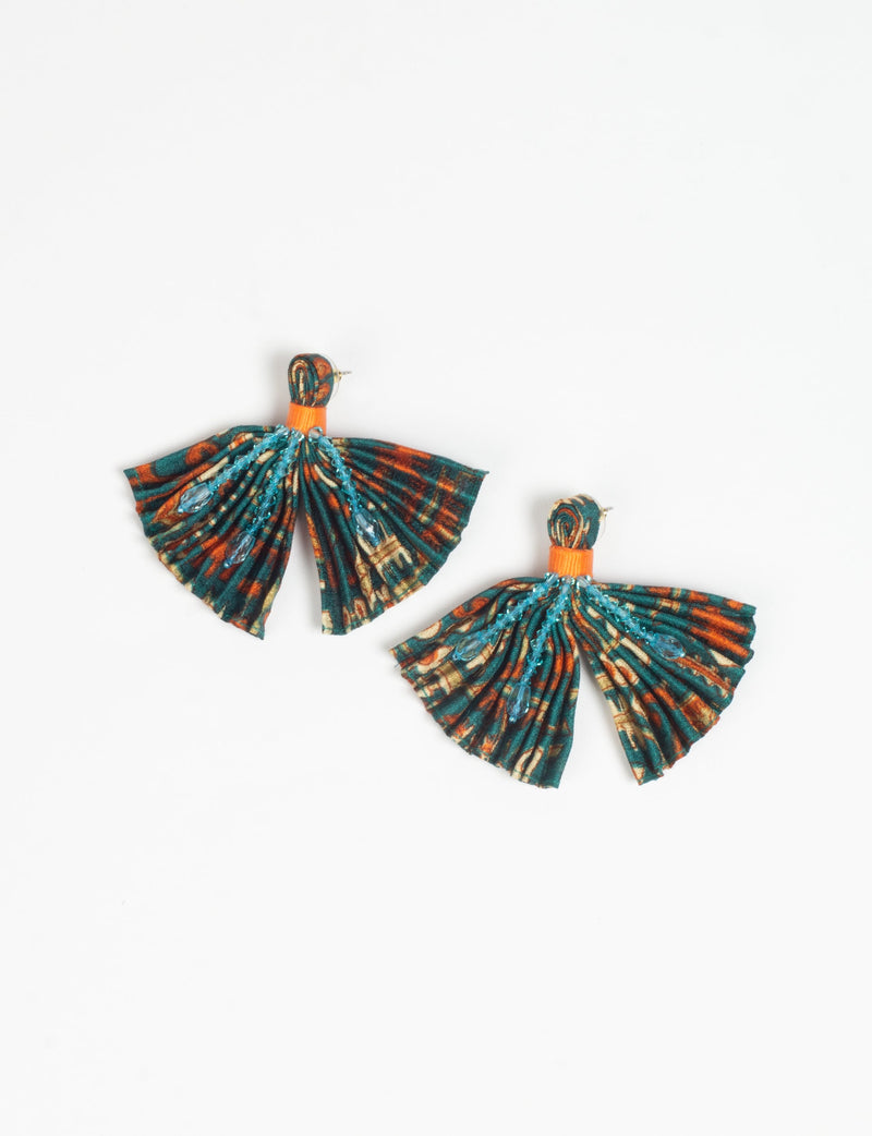 Pleated fabric earrings with green, orange, and beige micro design, blue bead embellishments, and orange band, flat lay view