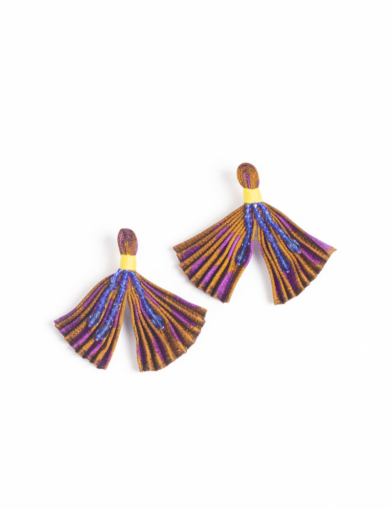 Yellow abstract pleated fabric earrings with purple and brown stripes and blue bead embellishments, flat lay on white background
