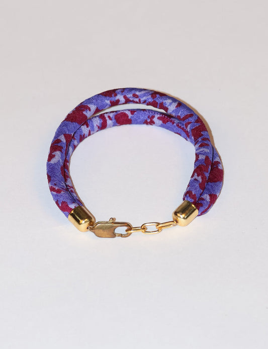 A close-up image of a hand wearing the Sari Rope bracelet, showcasing its colorful threads and unique design. This accessory embodies ethical fashion and sustainability, crafted from repurposed saris for a stylish and eco-conscious statement.