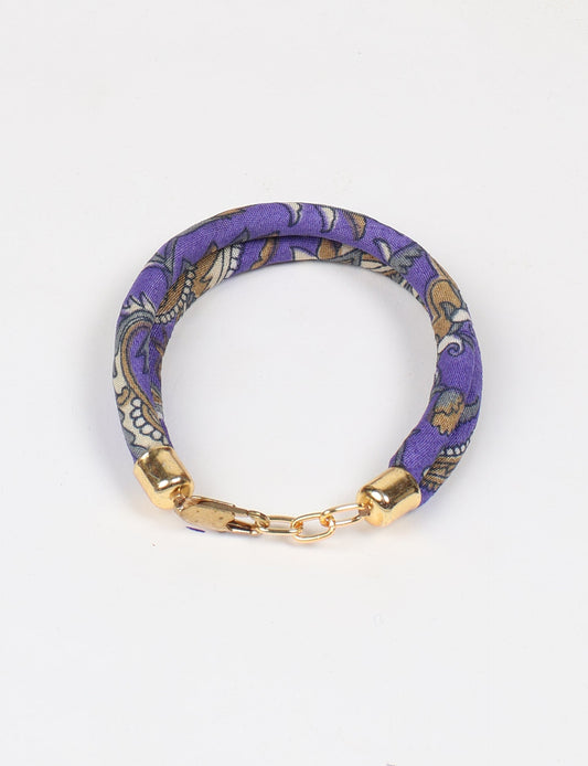 A close-up image of a hand wearing the Sari Rope bracelet, showcasing its colorful threads and unique design. This accessory embodies ethical fashion and sustainability, crafted from repurposed saris for a stylish and eco-conscious statement.