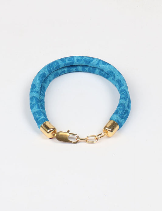 A close-up image of a hand wearing the Sari Rope bracelet, showcasing its colorful threads and unique design. This accessory embodies ethical fashion and sustainability, crafted from repurposed saris for a stylish and eco-conscious statement.