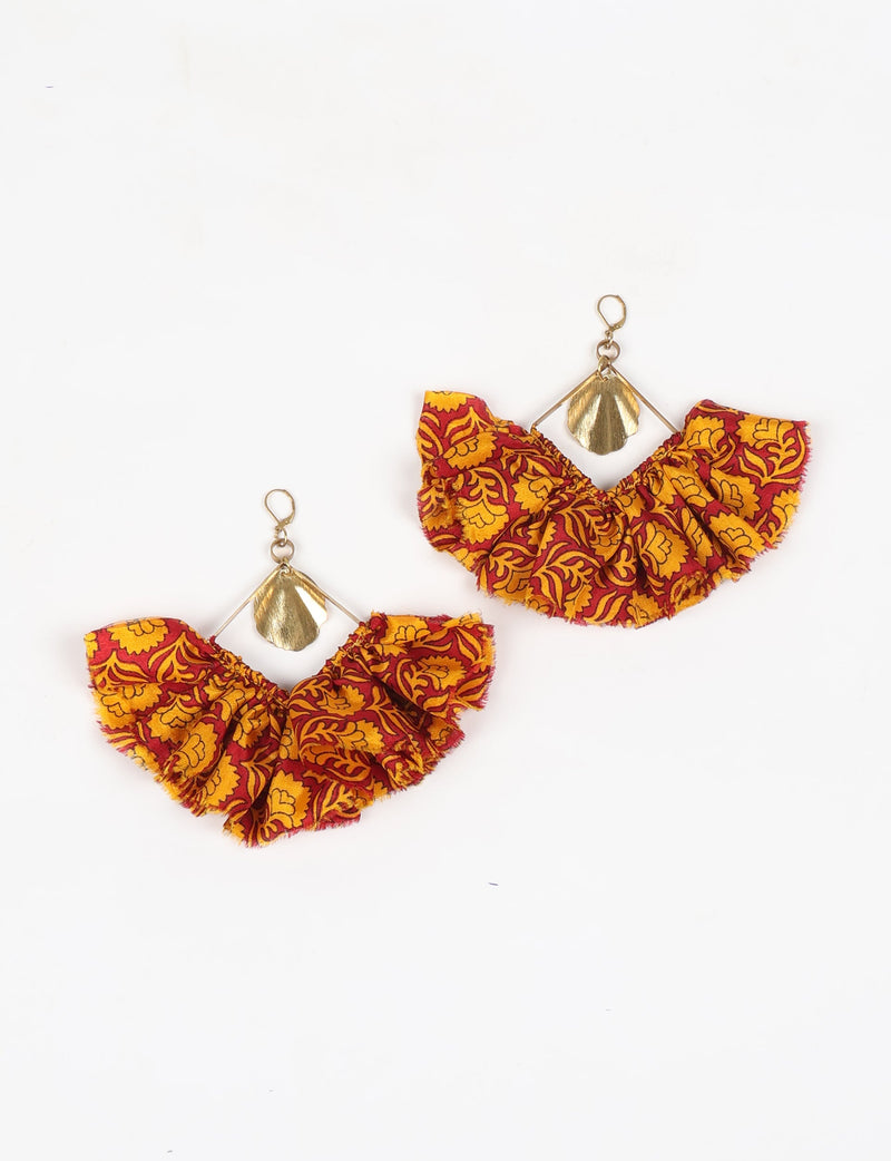 Maxi square earrings with red and yellow floral fabric ruffles and gold-tone metal shell charms, flat lay on white background