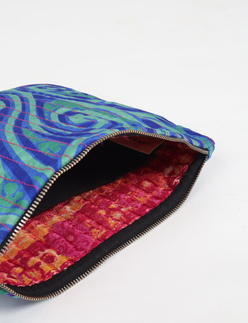 Quilted pouch with blue and green abstract pattern exterior, pink and orange textured interior, and metal zipper, flat lay view