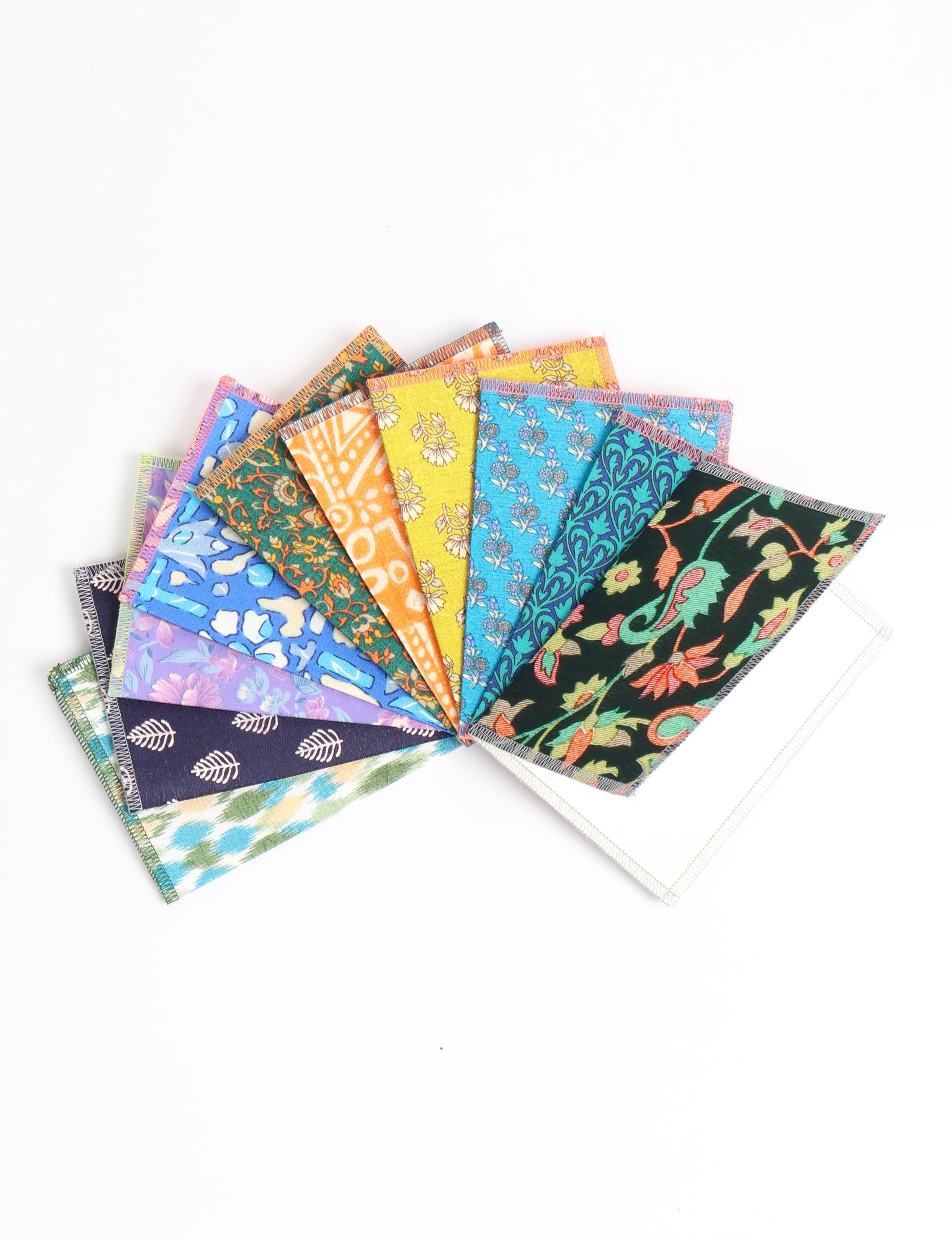 Set of ten folded postcards with colorful upcycled sari fabric covers in floral and geometric patterns, fanned on white background