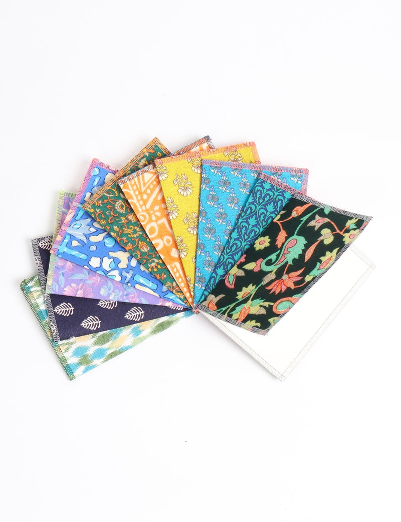 Set of ten folded postcards with colorful upcycled sari fabric covers in floral and geometric patterns, fanned on white background