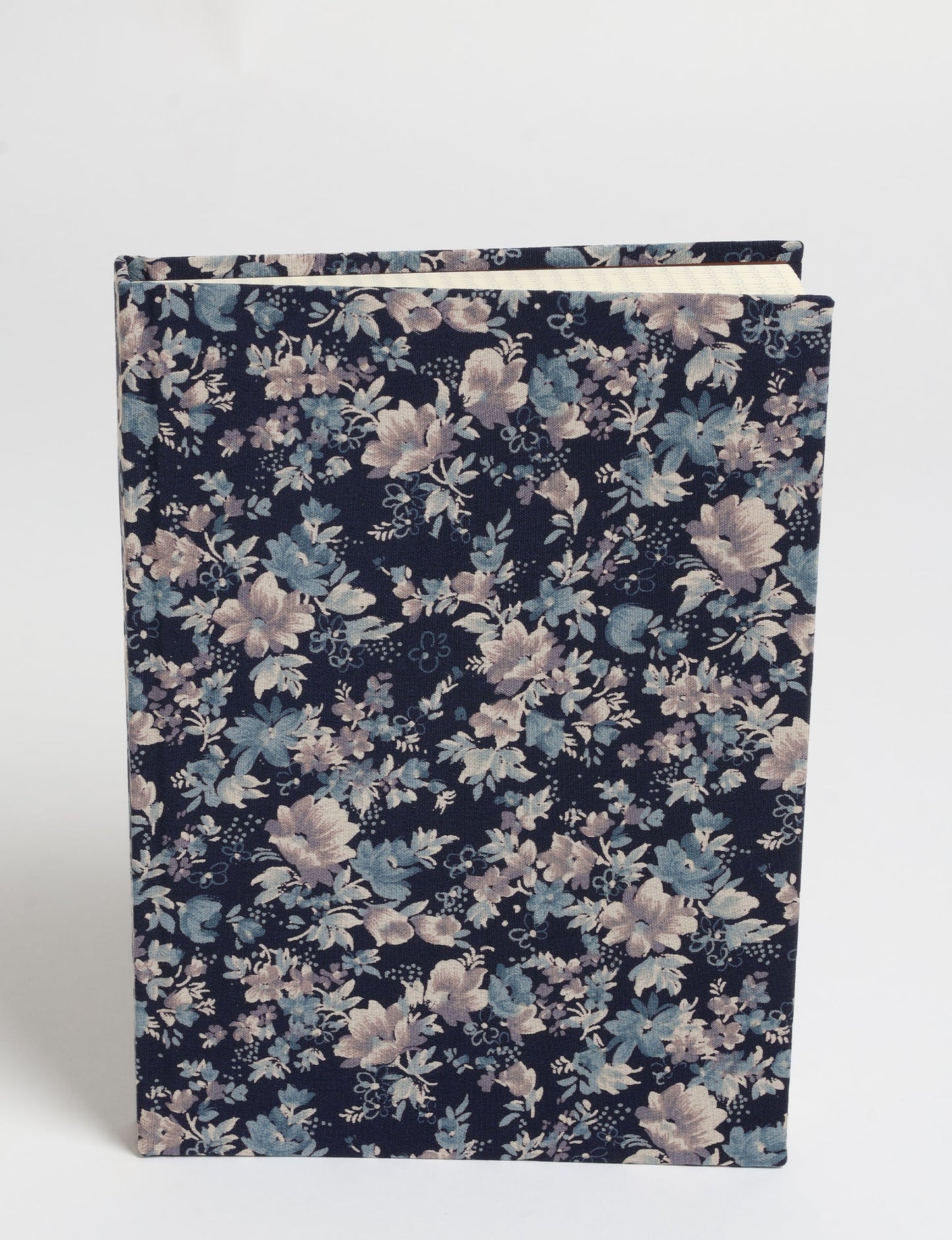 A5 hard cover notebook with blue floral fabric cover, shown standing upright with visible cream-colored pages