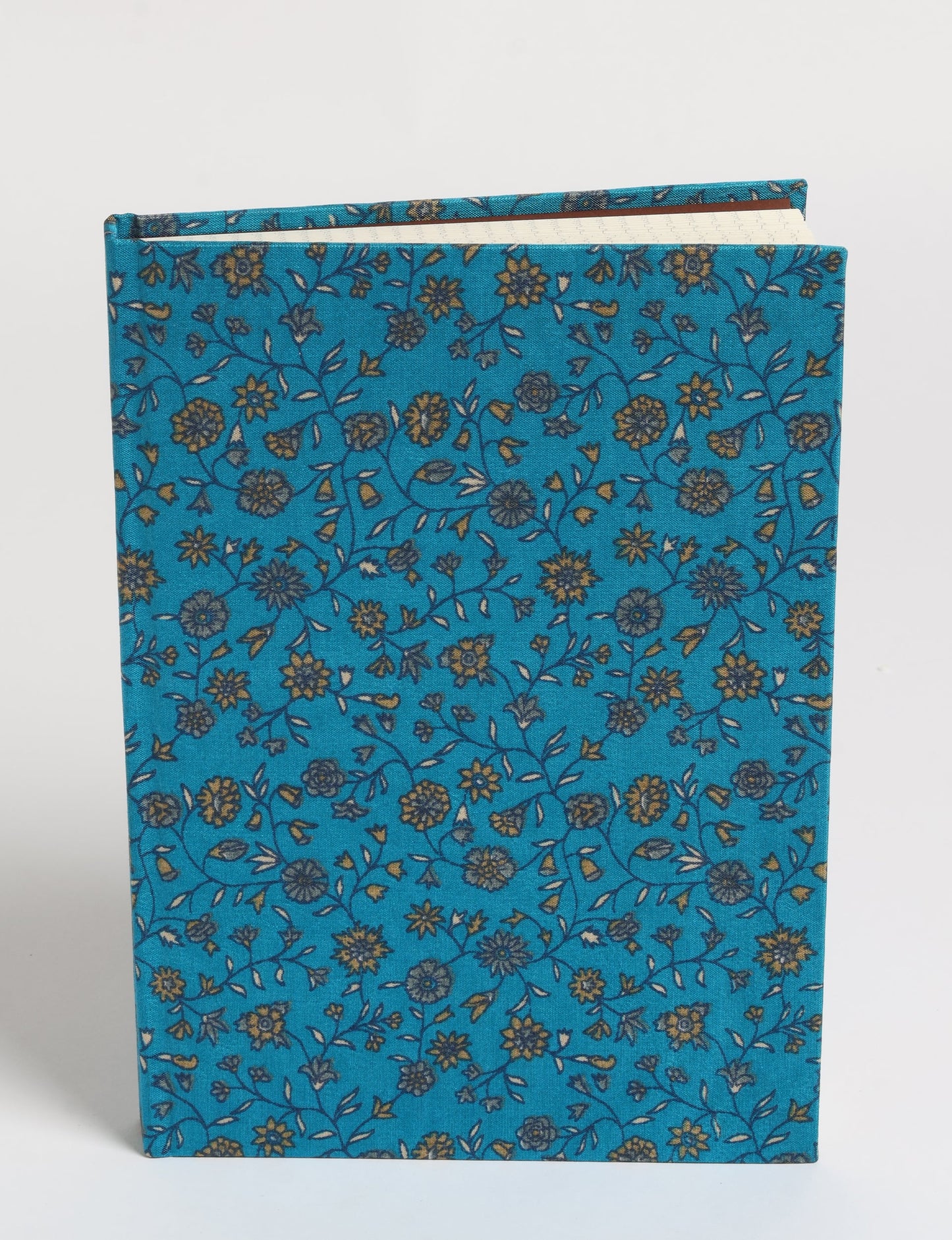 A5 hard cover notebook with blue fabric cover featuring a small floral pattern in yellow and gray, shown standing upright