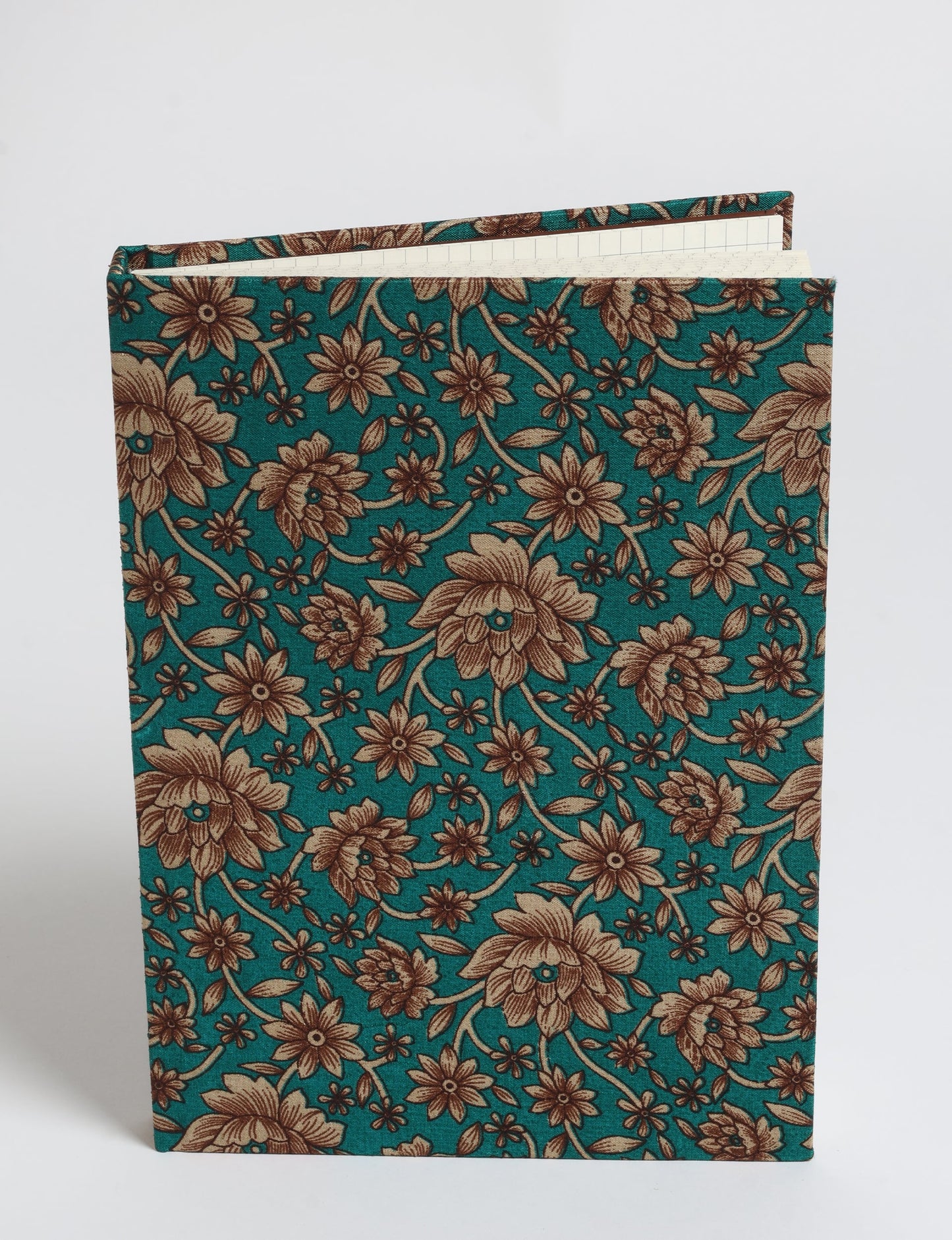 A5 hard cover notebook with green fabric cover featuring brown floral pattern, shown standing open with grid pages visible