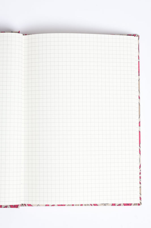 A5 hard cover notebook with blue floral fabric cover, open to blank grid pages, flat lay view on white background