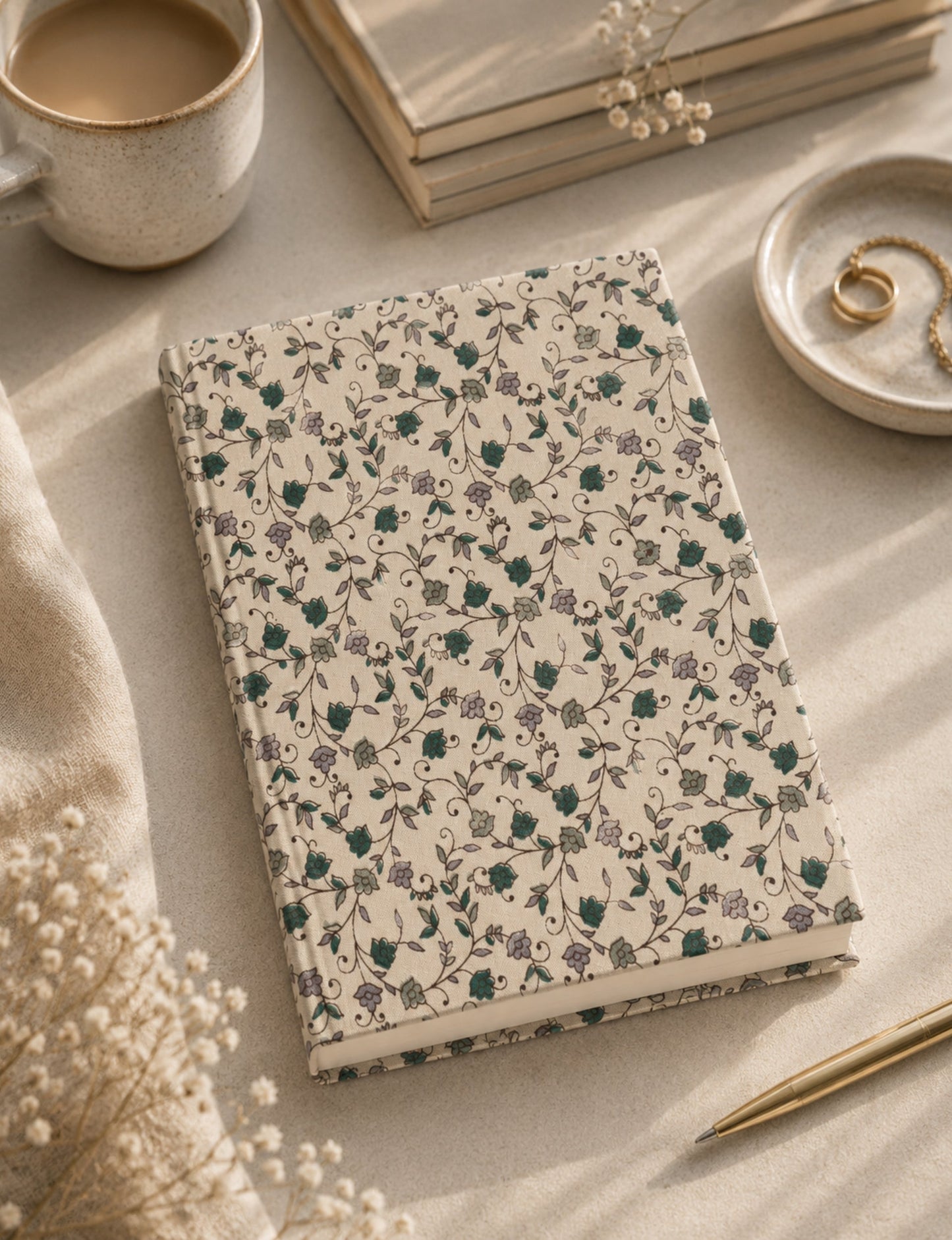 A5 hard cover notebook with green cover and beige floral pattern, shown closed on a wooden surface