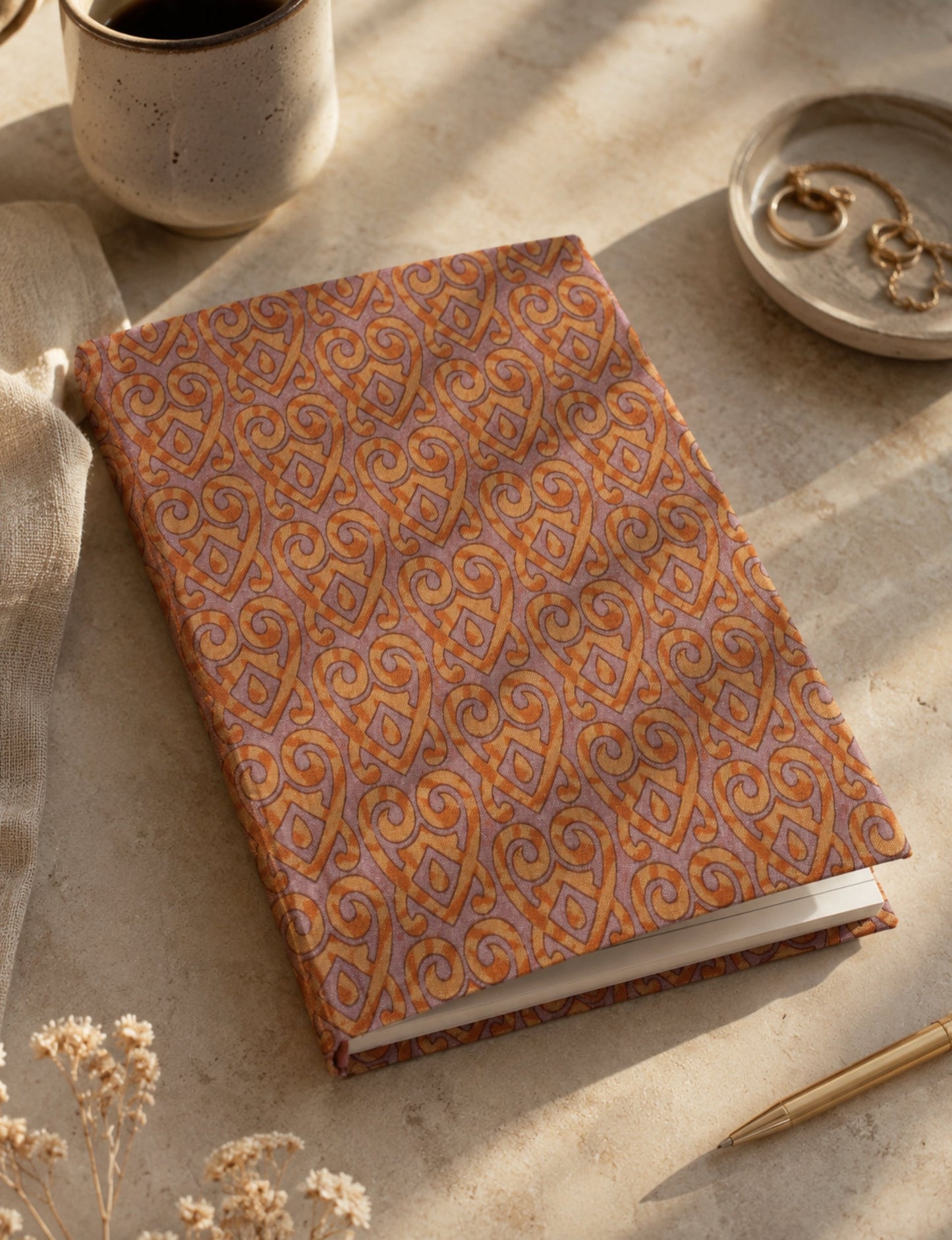 A5 hard cover notebook with green cover and beige floral pattern, shown closed on a wooden surface