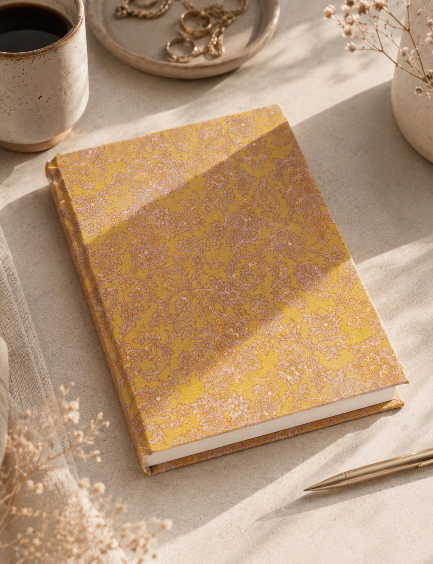 A5 hard cover notebook with green cover and beige floral pattern, shown closed on a wooden surface