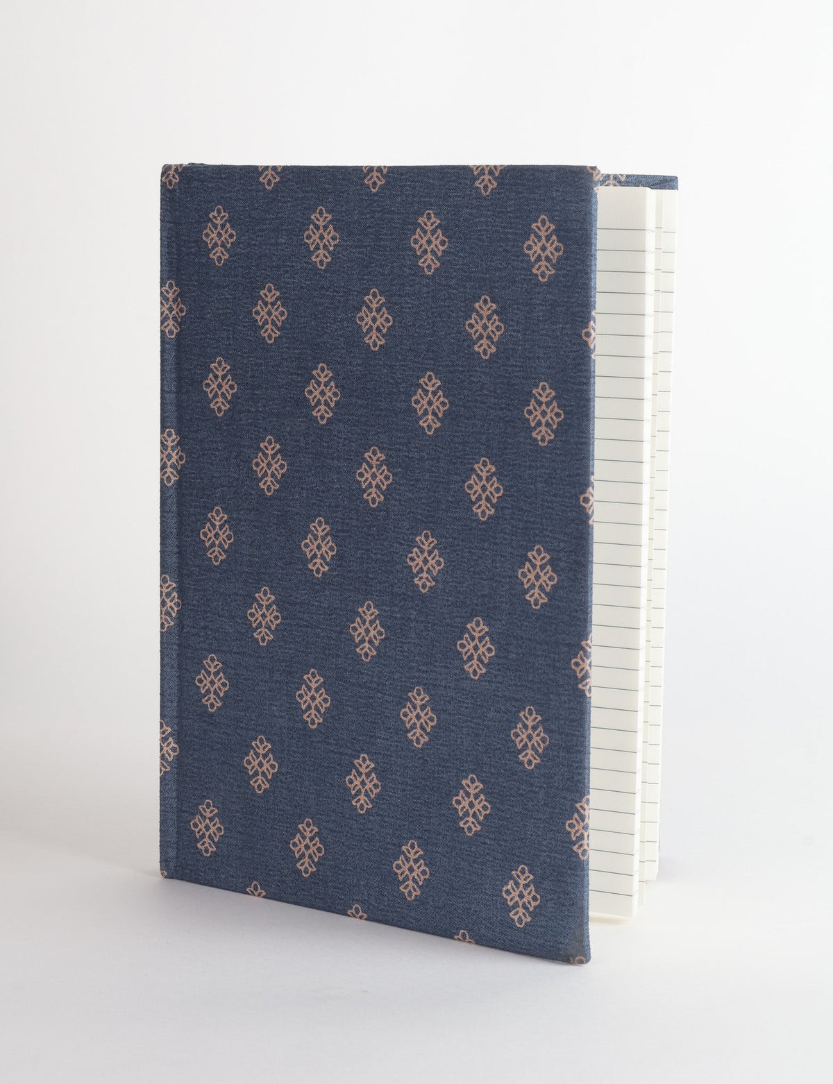 A5 hard cover notebook with blue fabric cover featuring a small brown geometric pattern, shown partially open with lined pages