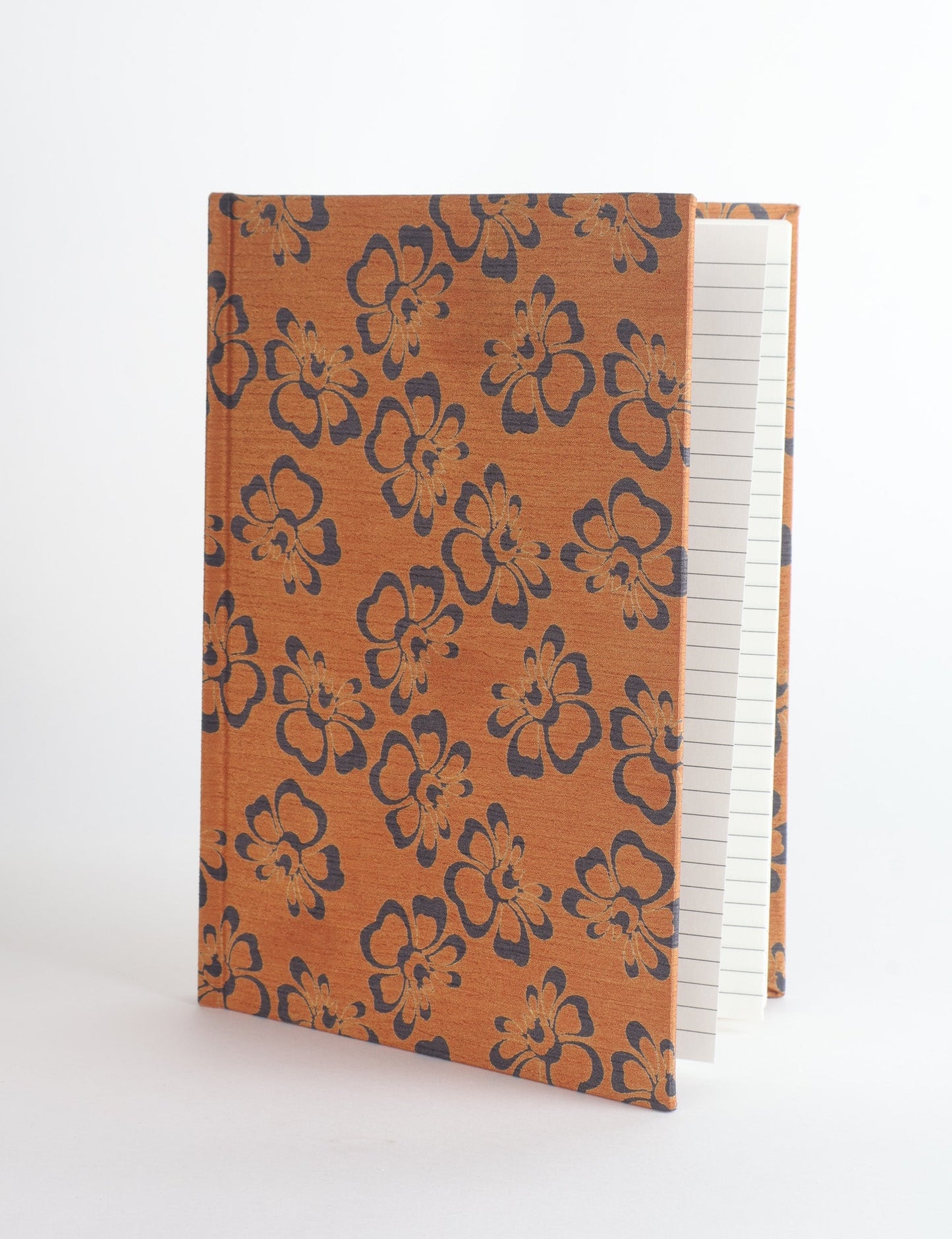 A5 hard cover notebook with green fabric cover featuring brown floral pattern, shown standing open with grid pages visible