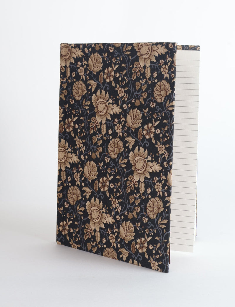 A5 hard cover notebook with dark blue cover featuring beige floral pattern, shown partially open with lined pages visible