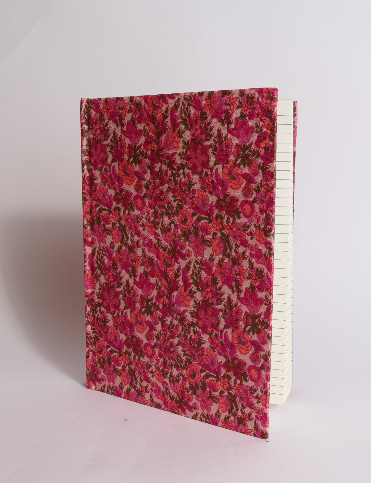 A5 hard cover notebook with dark blue cover featuring beige floral pattern, shown partially open with lined pages visible