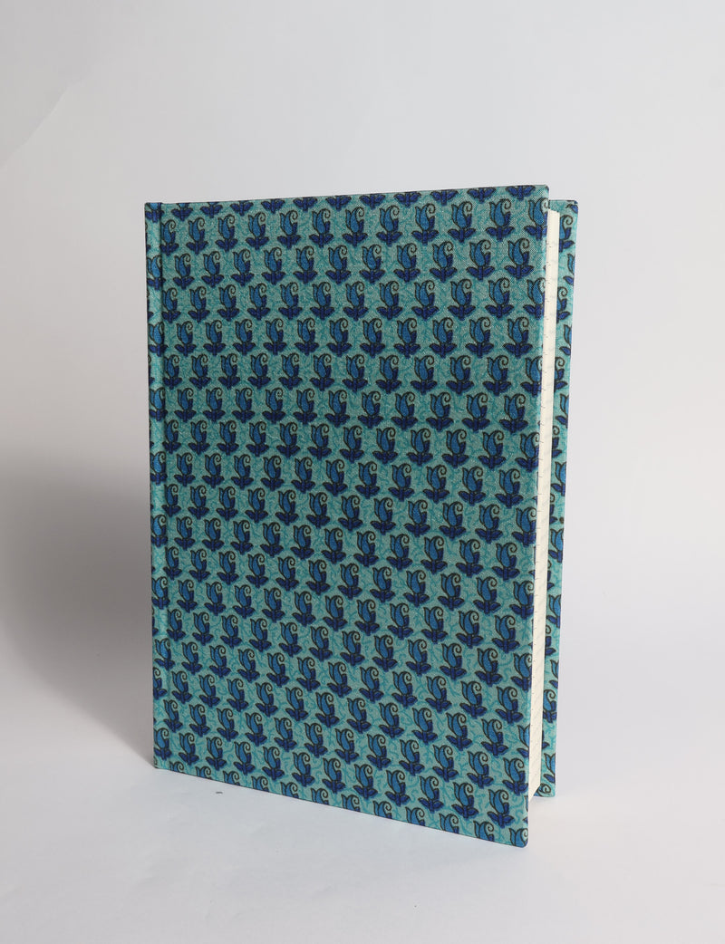 A5 hard cover notebook with dark blue cover featuring beige floral pattern, shown partially open with lined pages visible