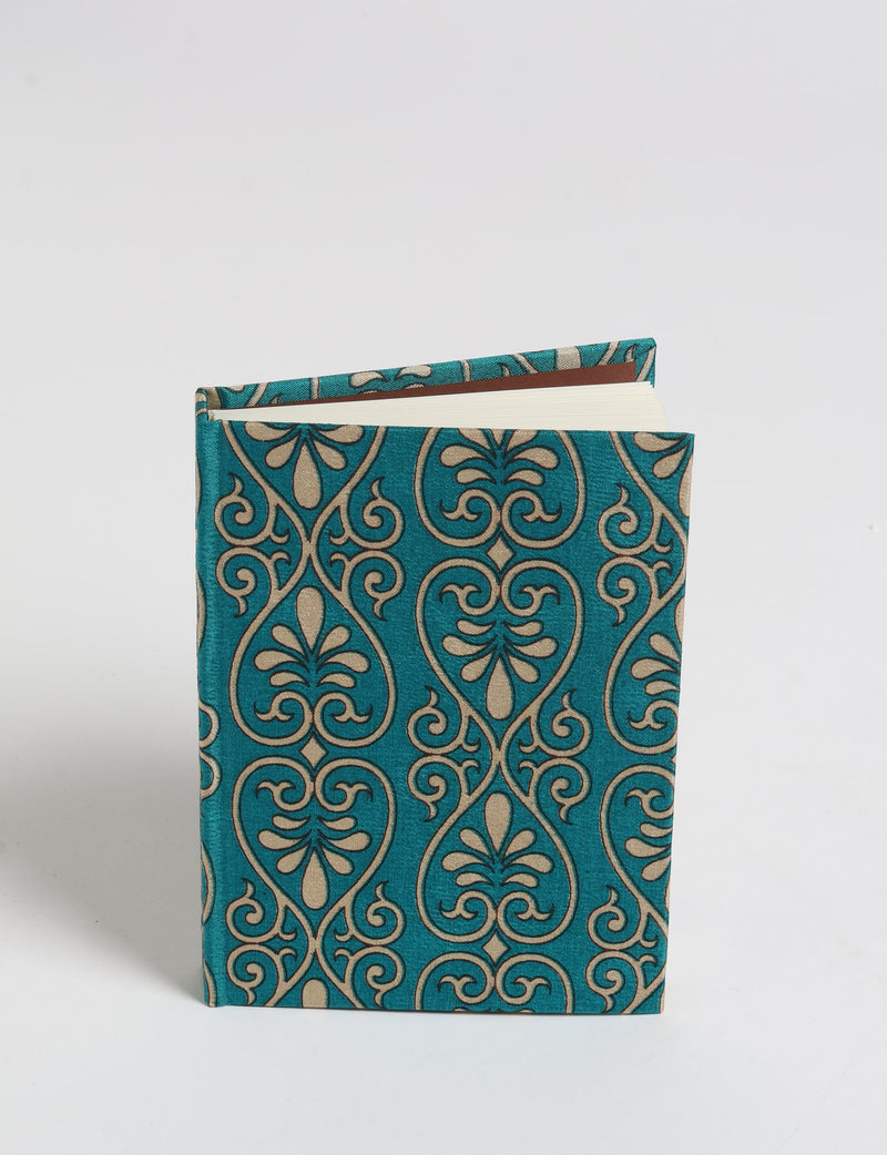 A6 hard cover notebook with teal and beige pre-loved sari fabric cover, shown standing with pages slightly open