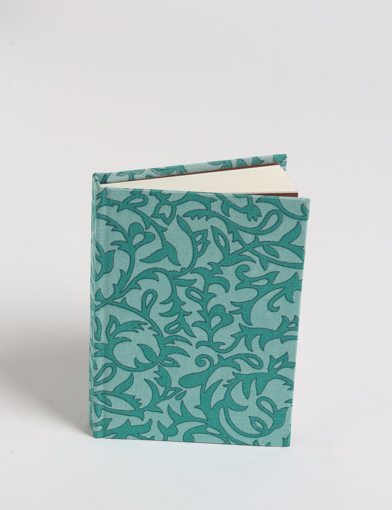 A6 hard cover notebook with teal pre-loved sari fabric cover featuring dark green floral vine pattern, standing upright