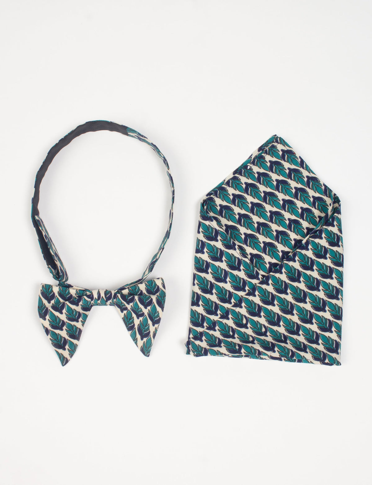 Green and navy blue leaf patterned bow tie and matching pocket square set, flat lay on white background