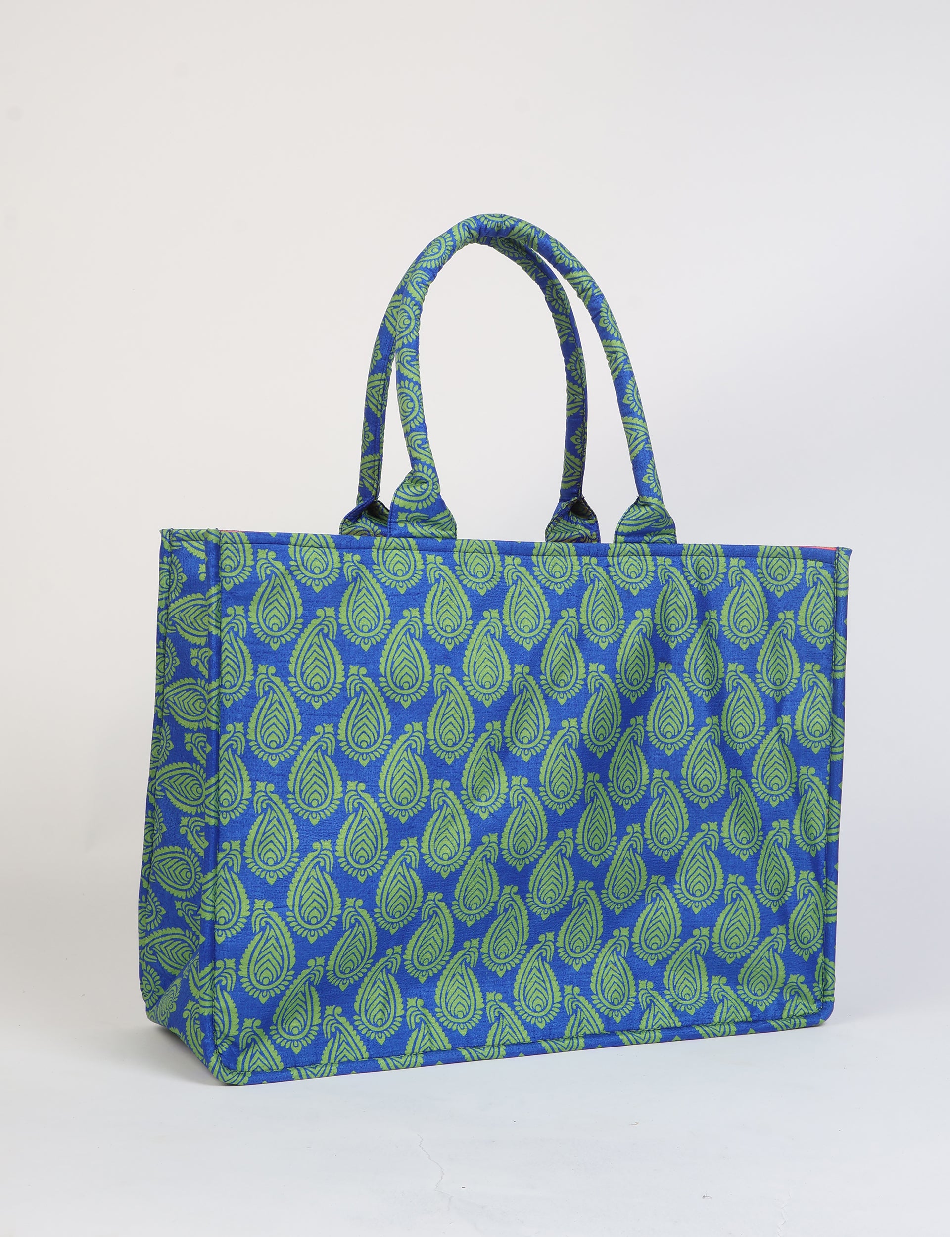 Blue tote bag with green paisley pattern, rectangular shape, and two padded handles, shown standing on a white surface