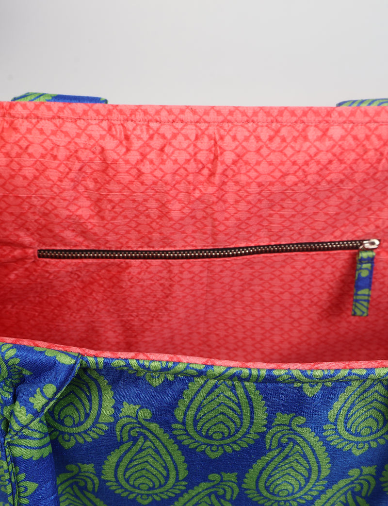 Blue and green paisley patterned work tote bag with coral pink interior lining and zippered pocket, flat view inside top edge