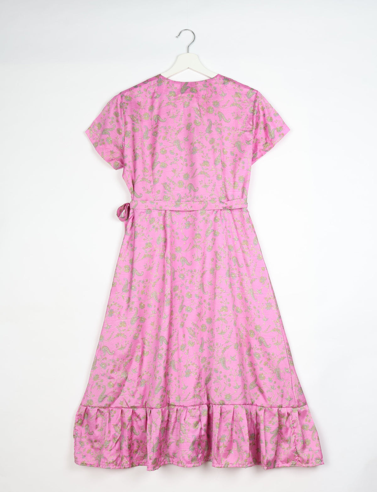 Pink midi wrap dress with gold floral and paisley print, short sleeves, waist tie, and ruffled hem, shown from back on