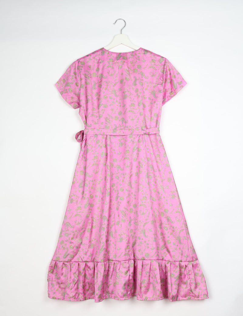 Pink midi wrap dress with gold floral and paisley print, short sleeves, waist tie, and ruffled hem, shown from back on