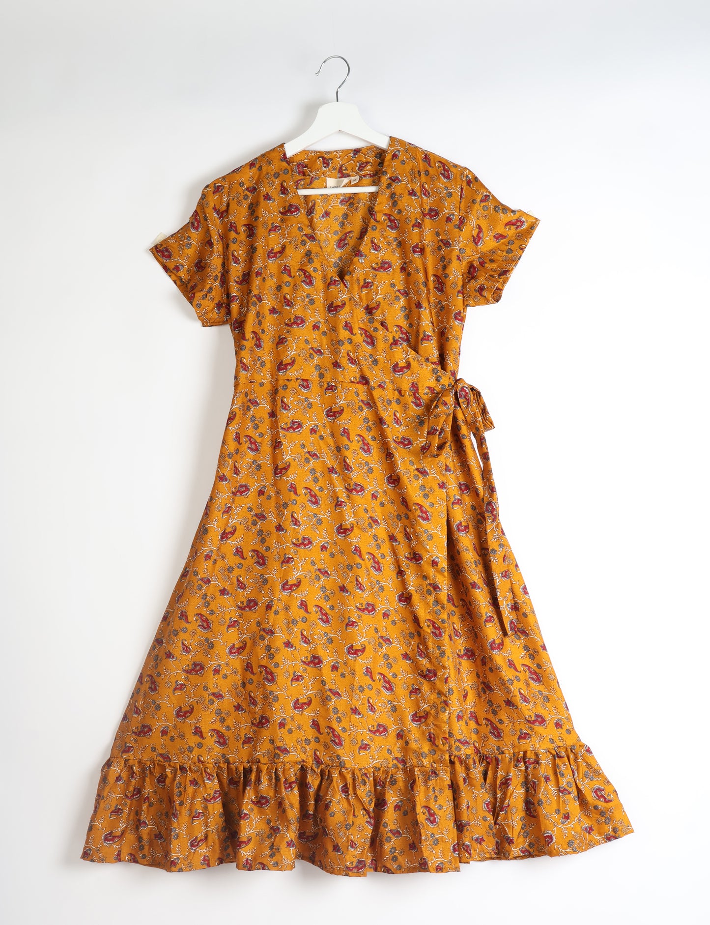 Embrace timeless elegance with our MIDI WRAP DRESS – a midi-length beauty featuring a v-neck, flattery from all angles, and a charming sari belt. Crafted from sustainable materials, this dress embodies ethical clothing and green fashion. Sophisticated with a frill tier at the hem and short cap sleeves, this dress is perfect for any occasion. Tie up the beautifully crafted sari belt on the side for a versatile, stylish, and eco-friendly look.