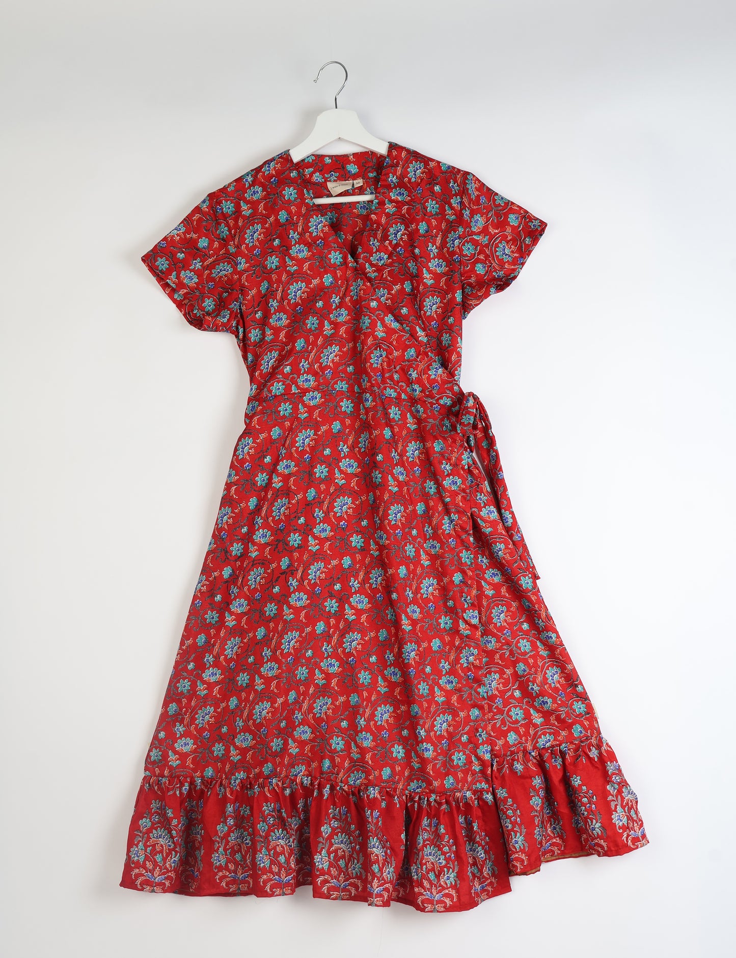 Embrace timeless elegance with our MIDI WRAP DRESS – a midi-length beauty featuring a v-neck, flattery from all angles, and a charming sari belt. Crafted from sustainable materials, this dress embodies ethical clothing and green fashion. Sophisticated with a frill tier at the hem and short cap sleeves, this dress is perfect for any occasion. Tie up the beautifully crafted sari belt on the side for a versatile, stylish, and eco-friendly look.