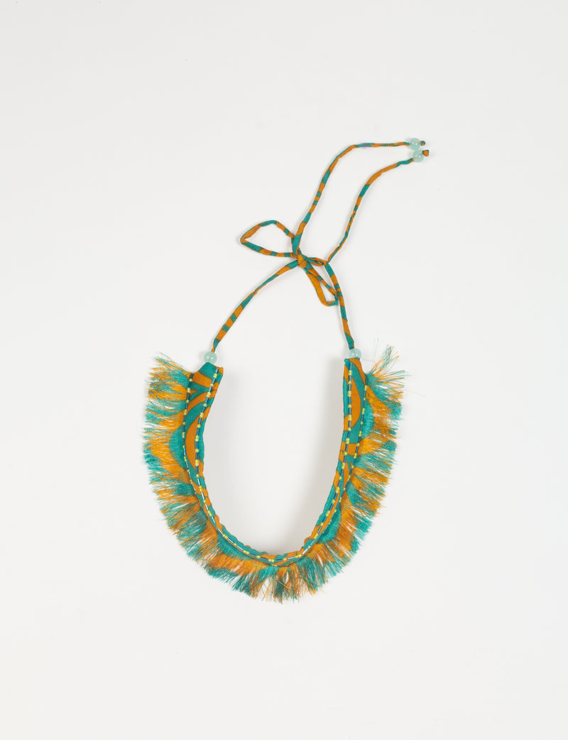 Yellow and teal abstract patterned fabric tie-up choker with fringe edges and bead details, flat lay on white background