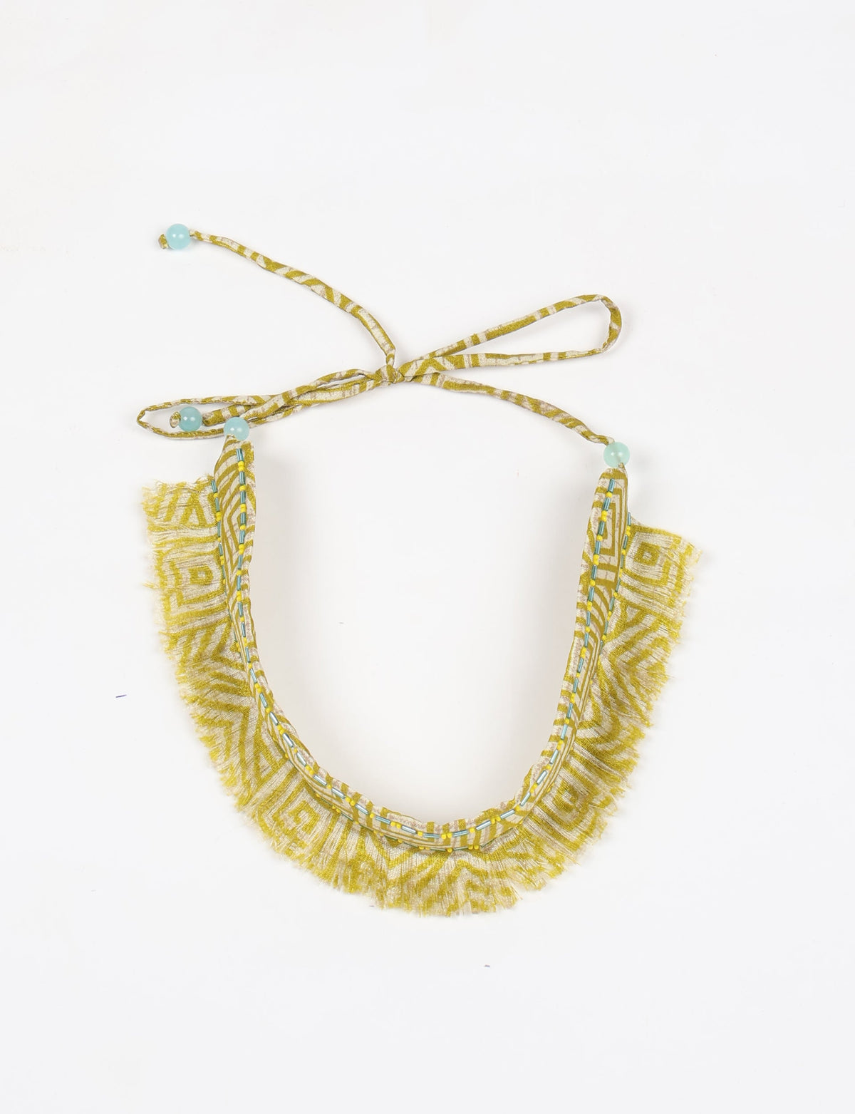 Yellow abstract patterned fabric choker with fringe edges, blue bead accents, and tie-up closure, flat lay on white background