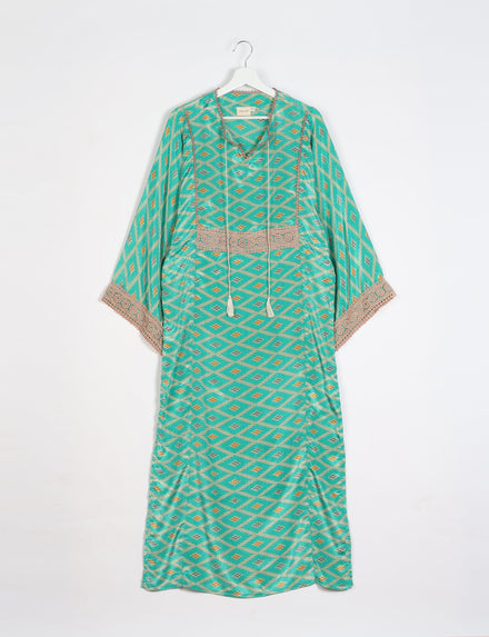 Green maxi kaftan with geometric diamond pattern, beige lace trim on sleeves and chest, hanging on white hanger