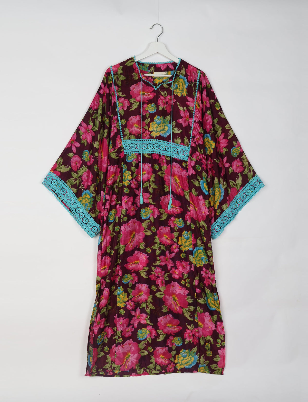 Brown maxi kaftan with pink, yellow, and blue floral print, turquoise lace trim on sleeves and chest, hanging front view