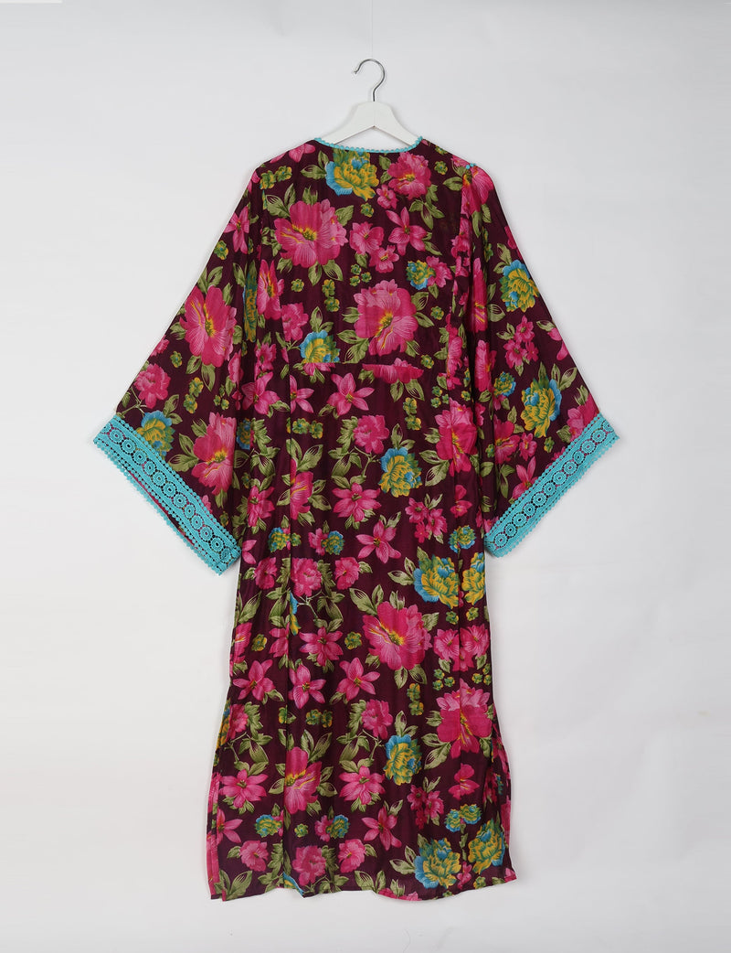 Maxi kaftan with brown base, bright pink and yellow floral print, turquoise lace trim on wide sleeves, shown hanging back view