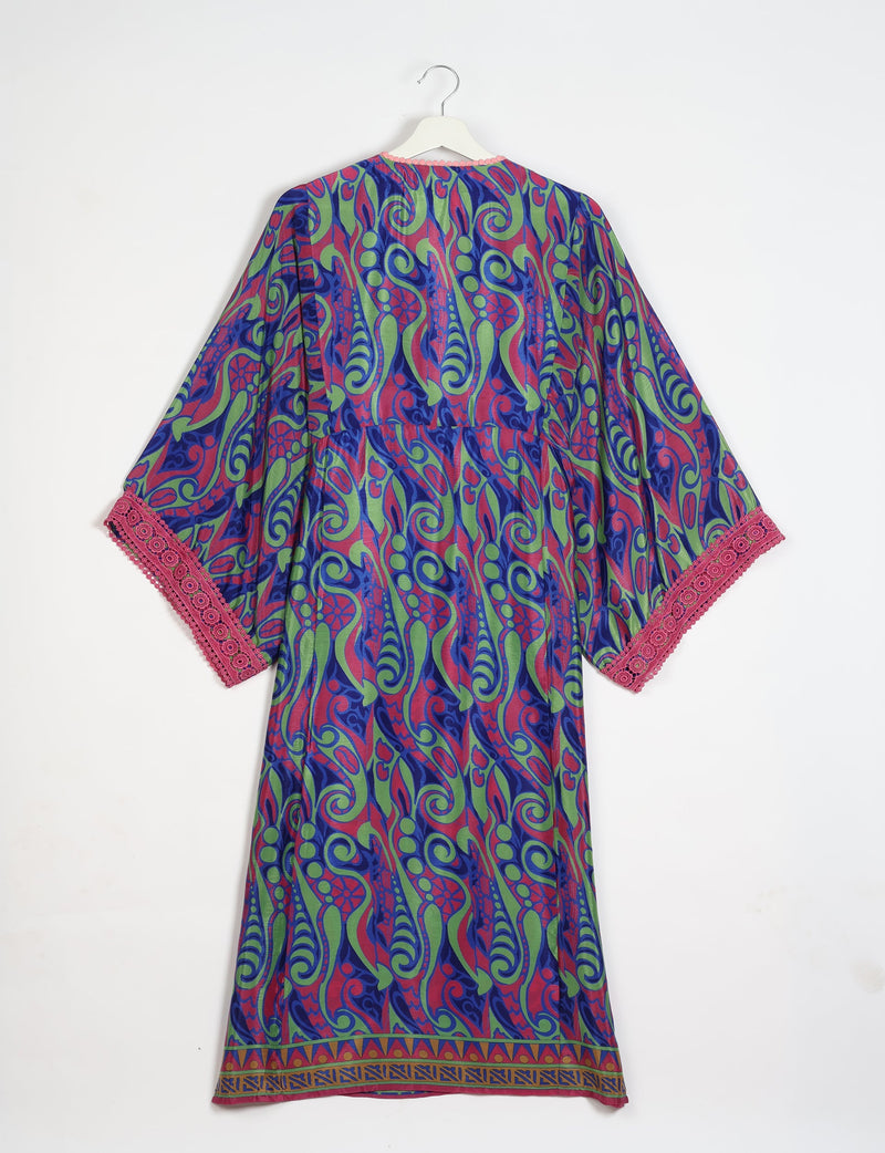 Maxi kaftan with blue, green, and red abstract swirl pattern, pink lace trim on sleeves, and geometric border hem, back view