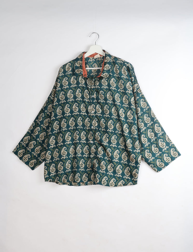 Green oversized shirt with beige paisley pattern, button front, and contrasting rust-colored inner collar, hanging on white