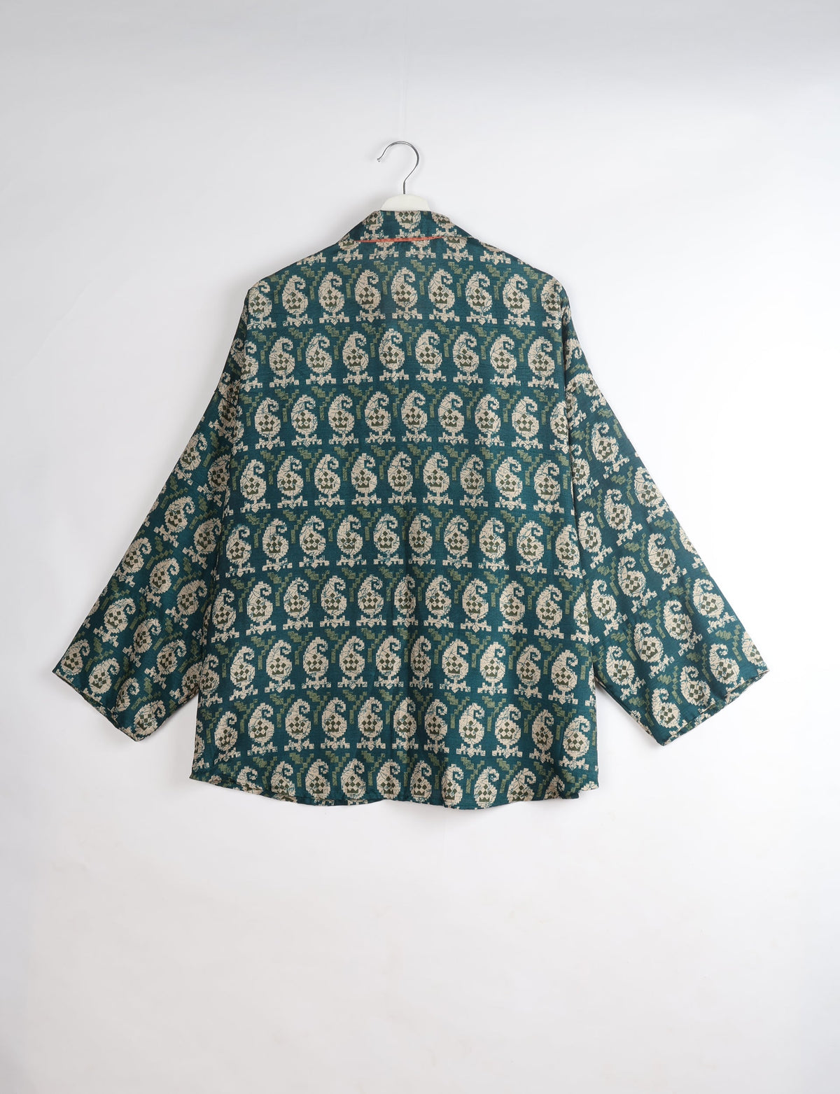Oversized green shirt with beige paisley pattern, long sleeves, and spread collar, shown from back on hanger