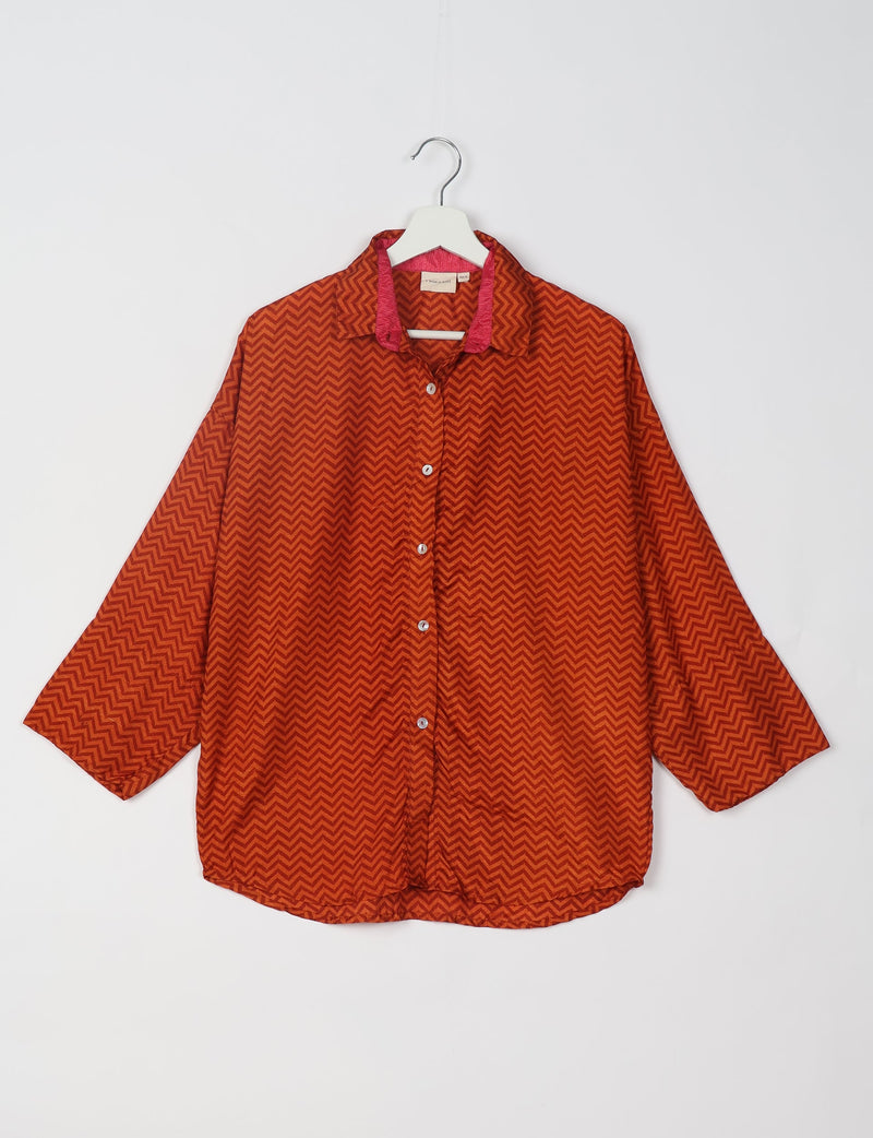 Oversized red shirt with geometric chevron pattern, button front, collar with pink inner lining, hanging on white hanger